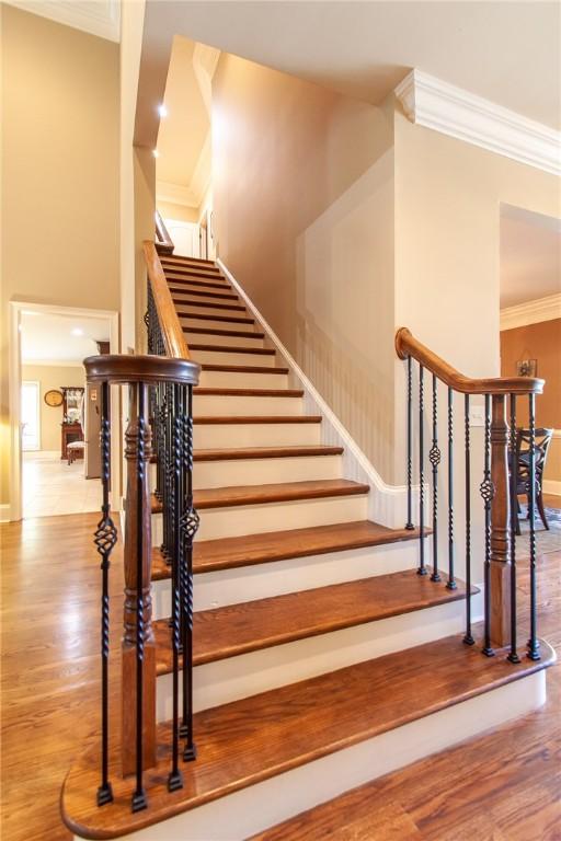 stairs featuring hardwood / wood-style flooring and crown molding