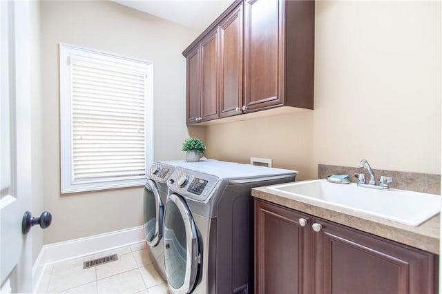 laundry area with cabinets, light tile patterned floors, sink, and washing machine and clothes dryer