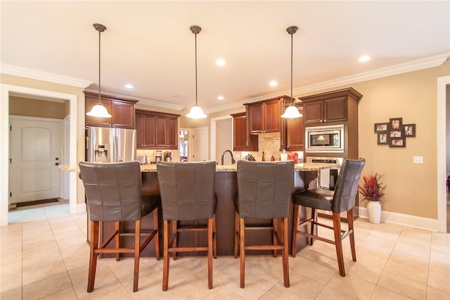 kitchen featuring a center island with sink, decorative light fixtures, and appliances with stainless steel finishes