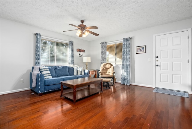 living room featuring ceiling fan, dark wood-type flooring, a textured ceiling, and a wealth of natural light