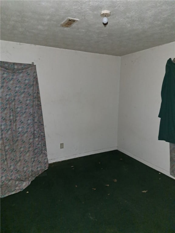 empty room with baseboards, visible vents, and a textured ceiling