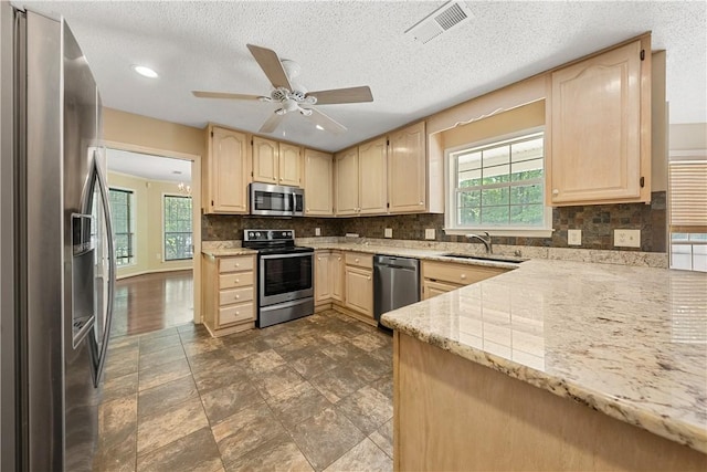 3519 Anderson Rd, Opelika, AL 36801 - kitchen featuring stainless steel appliances, light brown cabinets, healthy amount of natural light, light stone counters, and a textured ceiling