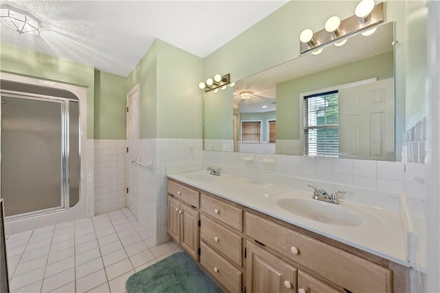 3519 Anderson Rd, Opelika, AL 36801 - bathroom with tile patterned floors, double vanity, a stall shower, tile walls, and wainscoting