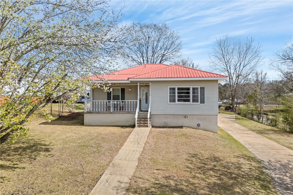 view of front of property featuring a porch, brick siding, and metal roof