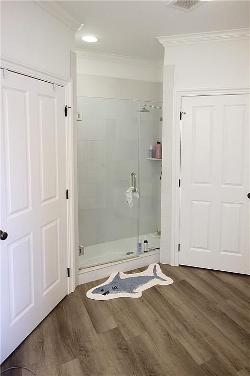 bathroom featuring wood-type flooring, walk in shower, and ornamental molding