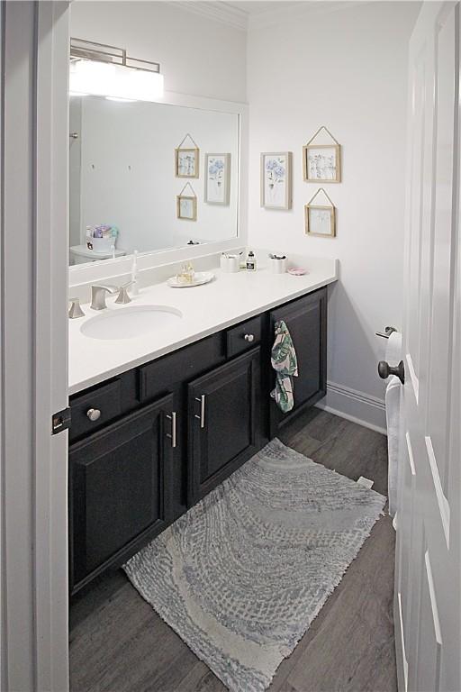 bathroom with hardwood / wood-style floors, vanity, and ornamental molding