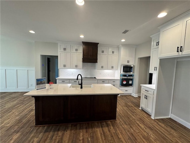 kitchen featuring white cabinetry, appliances with stainless steel finishes, and an island with sink