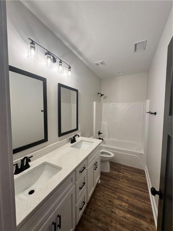 full bathroom featuring hardwood / wood-style flooring, vanity, tub / shower combination, and toilet