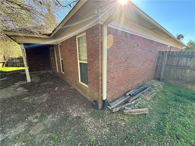 view of property exterior featuring fence and brick siding