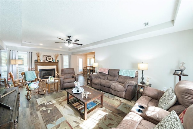 living room featuring ceiling fan, light hardwood / wood-style flooring, and a tray ceiling