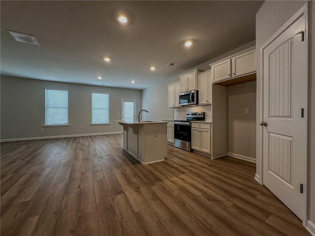 kitchen featuring a kitchen island with sink, a sink, white cabinetry, light countertops, and appliances with stainless steel finishes