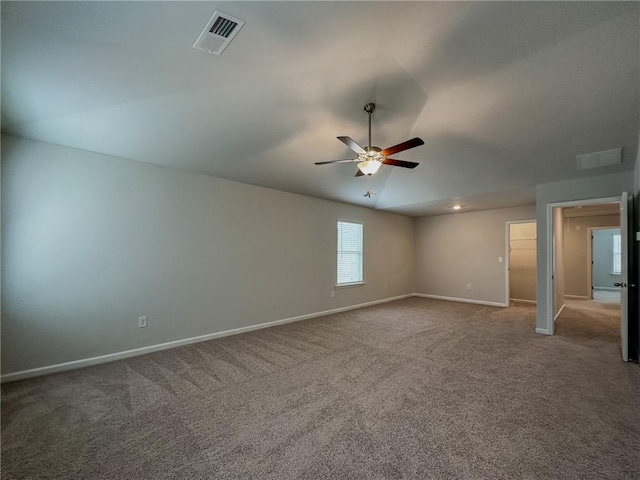 carpeted empty room featuring ceiling fan, vaulted ceiling, visible vents, and baseboards