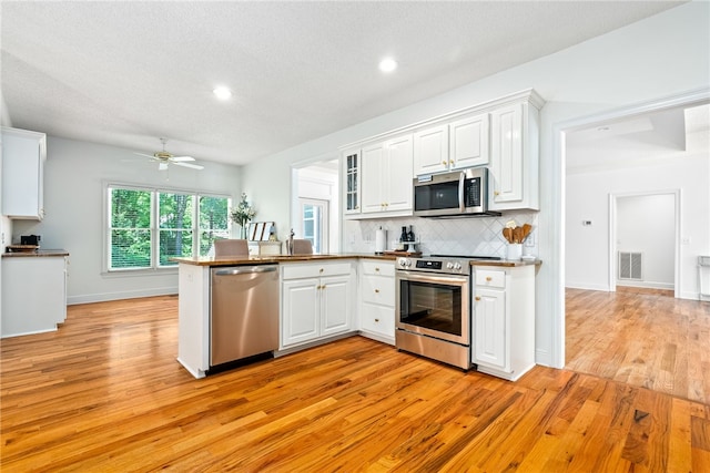 1421 Crossing Way, Auburn, AL 36830 - kitchen featuring stainless steel appliances, a peninsula, light wood-type flooring, recessed lighting, and a textured ceiling