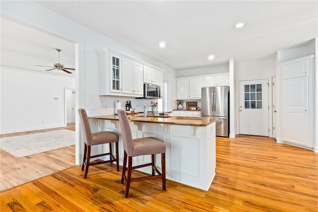 1421 Crossing Way, Auburn, AL 36830 - kitchen with stainless steel appliances, light wood-style flooring, a peninsula, glass insert cabinets, and white cabinetry