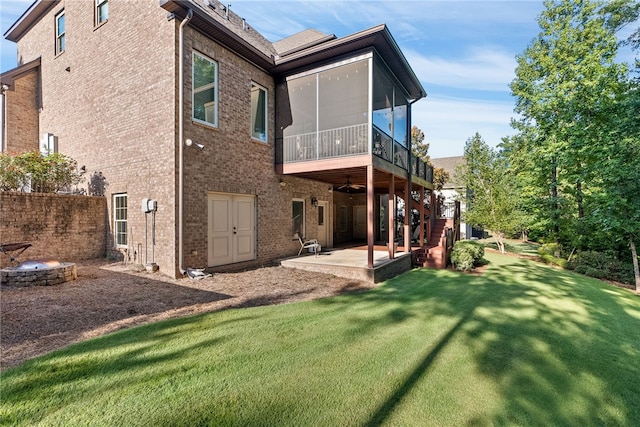 rear view of property featuring a lawn, a sunroom, and a patio area