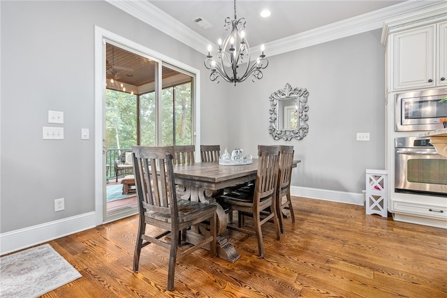 dining room featuring hardwood / wood-style flooring, crown molding, and a notable chandelier