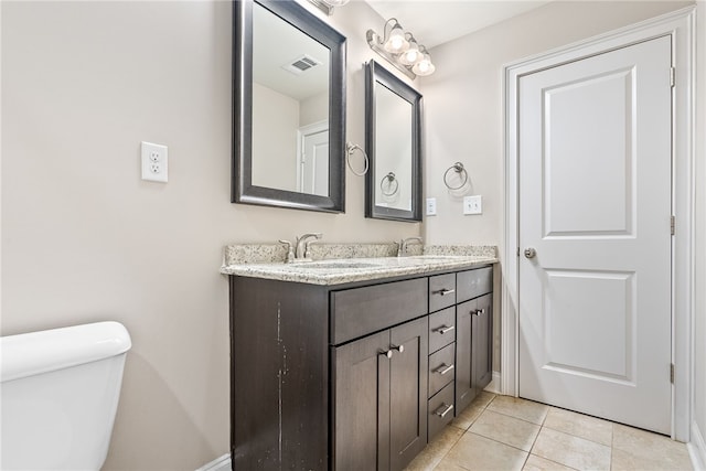 bathroom featuring tile patterned flooring, toilet, a sink, visible vents, and double vanity