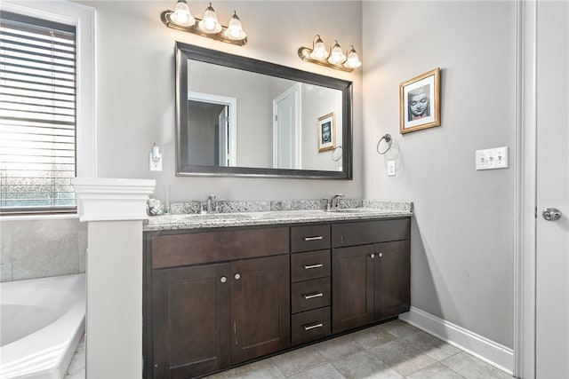 bathroom with a bathing tub, a sink, baseboards, and double vanity