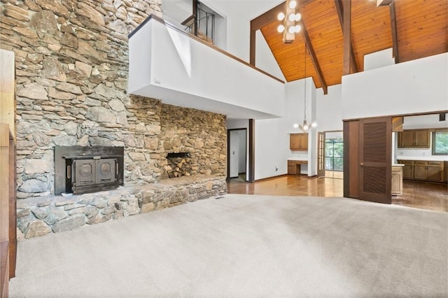 711 Oak Knoll Cir, Auburn, AL 36830 - unfurnished living room with carpet, high vaulted ceiling, a wood ceiling with exposed beams, wood finished floors, and a wood stove