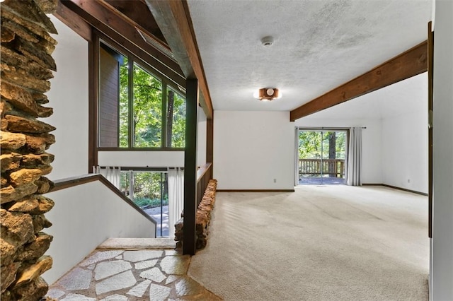 711 Oak Knoll Cir, Auburn, AL 36830 - unfurnished living room with carpet floors, beam ceiling, plenty of natural light, and a textured ceiling