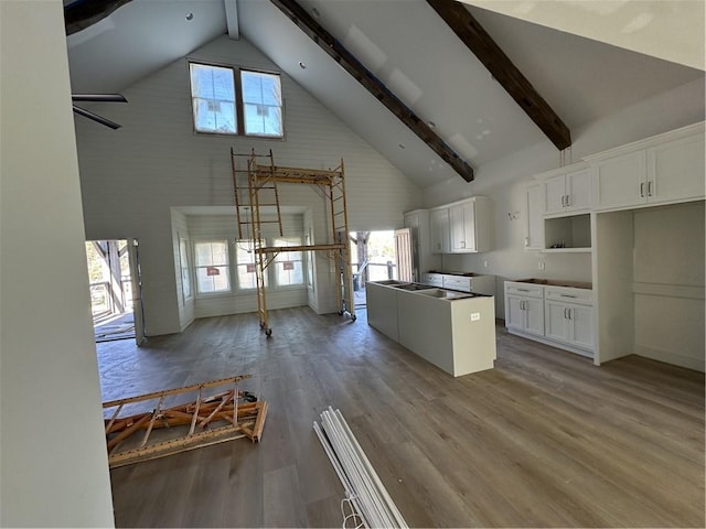 kitchen featuring beamed ceiling, white cabinetry, light hardwood / wood-style flooring, and high vaulted ceiling