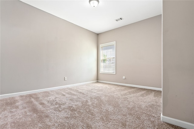 spare room with carpet floors, visible vents, and baseboards