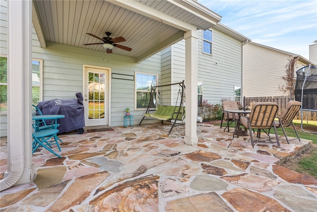 view of patio with outdoor dining space, grilling area, a ceiling fan, and a trampoline