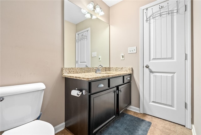 half bath featuring toilet, tile patterned floors, vanity, and baseboards