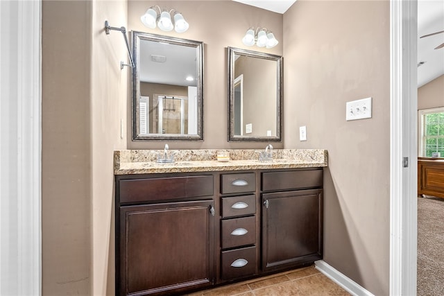 bathroom featuring a sink, tile patterned flooring, double vanity, and baseboards