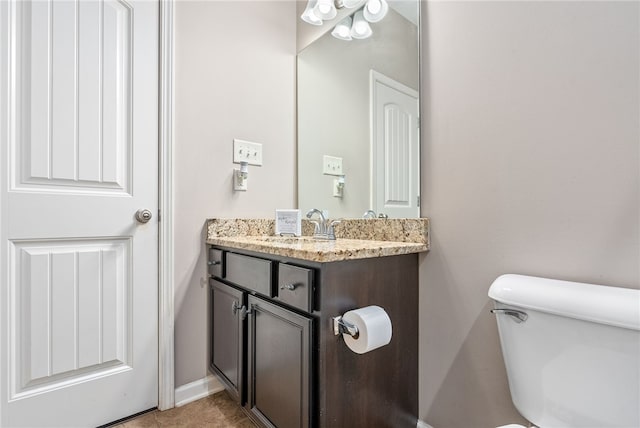 bathroom with toilet, vanity, and baseboards