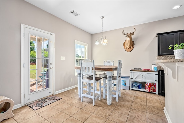 dining room featuring light tile patterned flooring, visible vents, a chandelier, and baseboards
