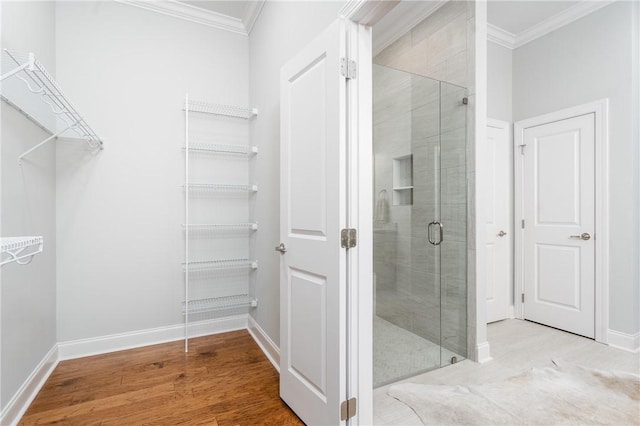 bathroom with hardwood / wood-style floors, a shower with shower door, and ornamental molding