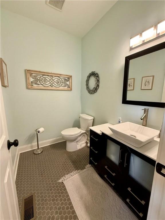 bathroom with toilet, vanity, and baseboards