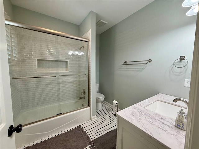 bathroom with toilet, bath / shower combo with glass door, vanity, and baseboards
