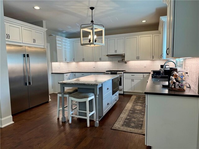 kitchen featuring high quality appliances, a chandelier, white cabinetry, a center island, and dark wood-style floors