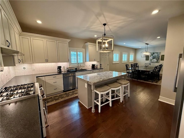 kitchen featuring stainless steel appliances, a sink, a chandelier, a kitchen island, and plenty of natural light