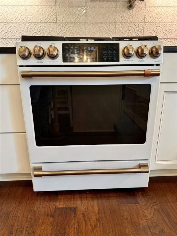 kitchen view of electric range, white cabinetry, and dark wood-style floors