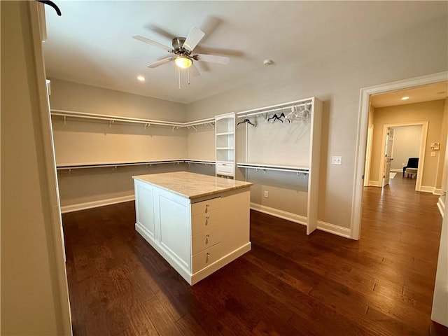spacious closet with dark wood-type flooring and ceiling fan
