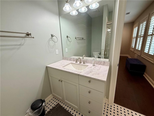 bathroom with baseboards, vanity, toilet, and a shower