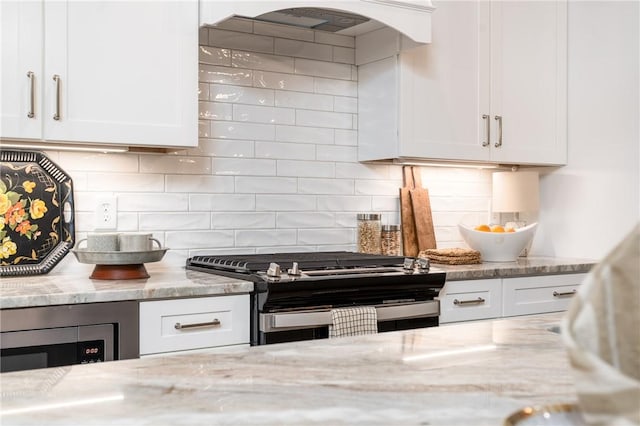 kitchen with stainless steel range with gas stovetop, light stone counters, and white cabinets