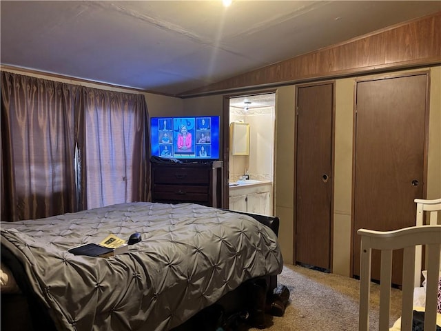 carpeted bedroom featuring a closet, vaulted ceiling, and ensuite bathroom