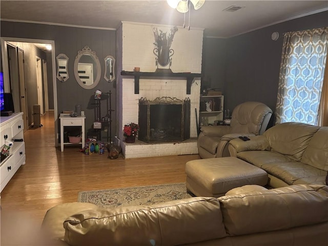 living room with hardwood / wood-style flooring, crown molding, and a fireplace