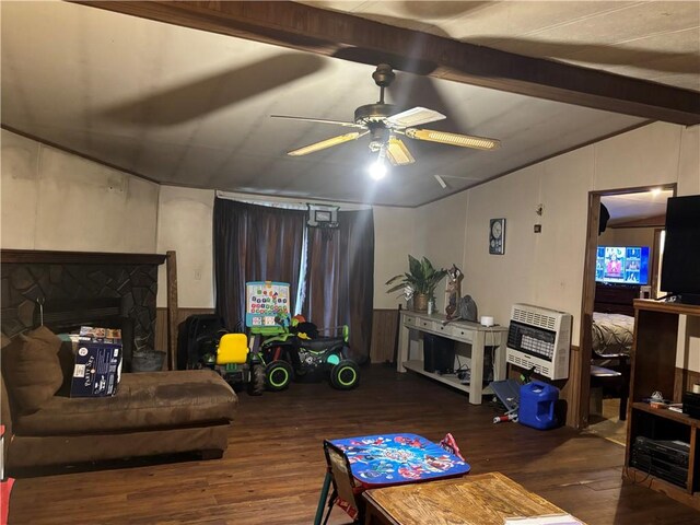 living room with a stone fireplace, ceiling fan, dark hardwood / wood-style flooring, lofted ceiling with beams, and heating unit