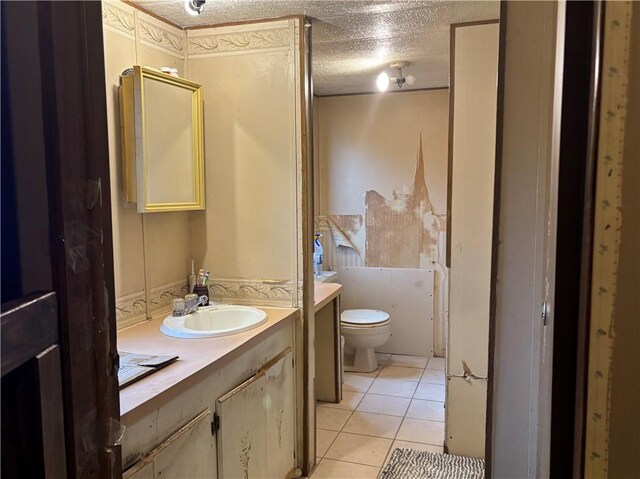 bathroom featuring tile patterned floors, a textured ceiling, toilet, and vanity