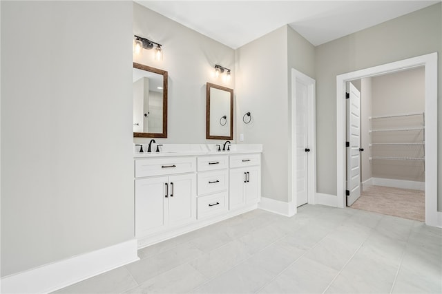 bathroom with double vanity, baseboards, and a sink