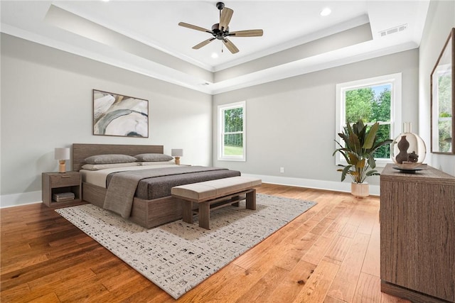 bedroom featuring a tray ceiling, visible vents, and light wood finished floors