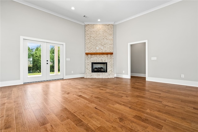 unfurnished living room featuring a large fireplace, wood finished floors, visible vents, baseboards, and crown molding