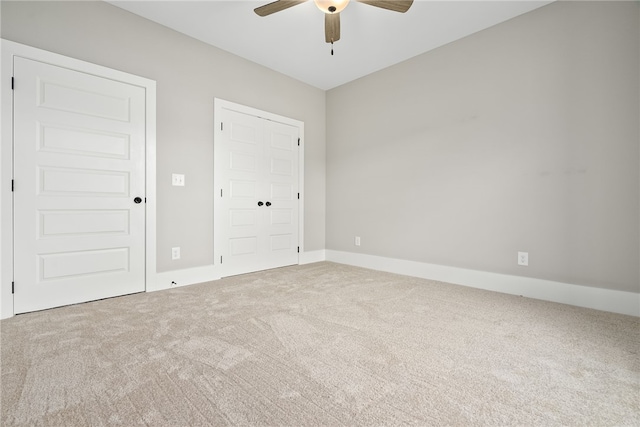 carpeted empty room with a ceiling fan and baseboards