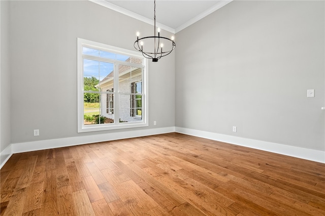 unfurnished dining area with a notable chandelier, baseboards, wood finished floors, and ornamental molding