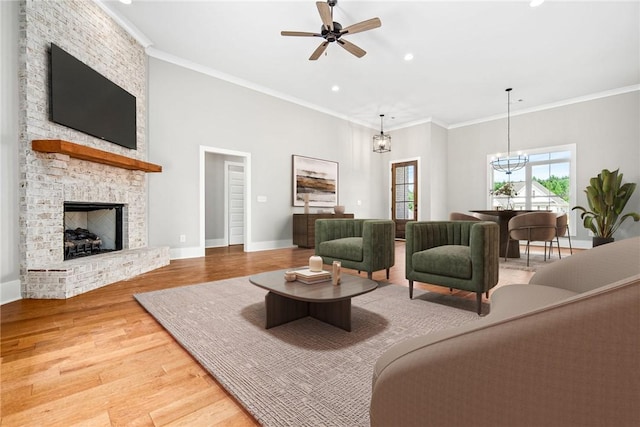 living area featuring ornamental molding, a brick fireplace, wood finished floors, and baseboards